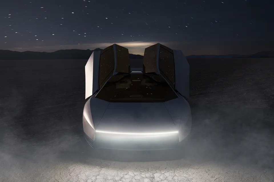Roadster head-on at night, canopy raised, its concealed headlights reading as one thin light bar.