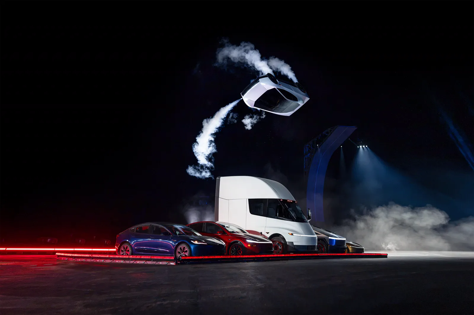 Roadster airborne over a Tesla Semi, a twisting trail of thruster gas behind it.